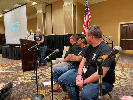 Larry Trimble giving a talk about his return to Vietnam, standing beside Team Gambler members Bruce, Xuan, Hayden, Marianne, and Rob