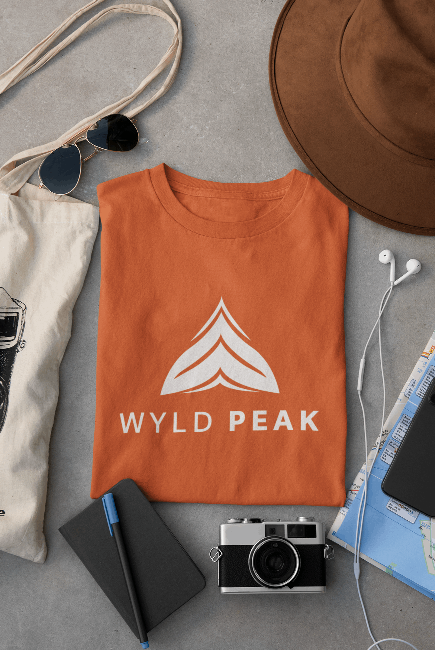 Wyld Peak Active men’s organic cotton t-shirt in orange laid flat on a desk