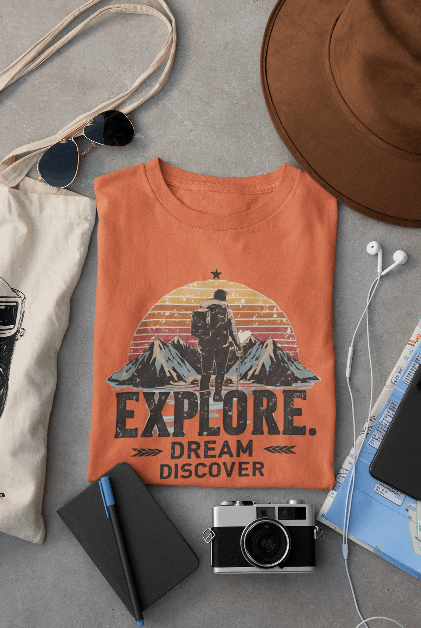 Wyld Peak Explorers men’s organic cotton t-shirt in orange laid flat on a desk