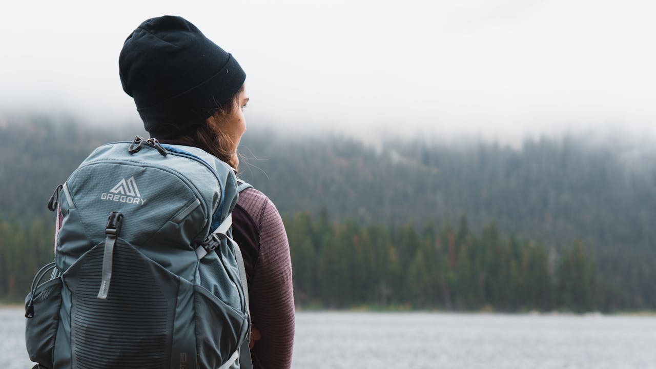 Solo hiker near a reflective lake in the Pacific Northwest wilderness.