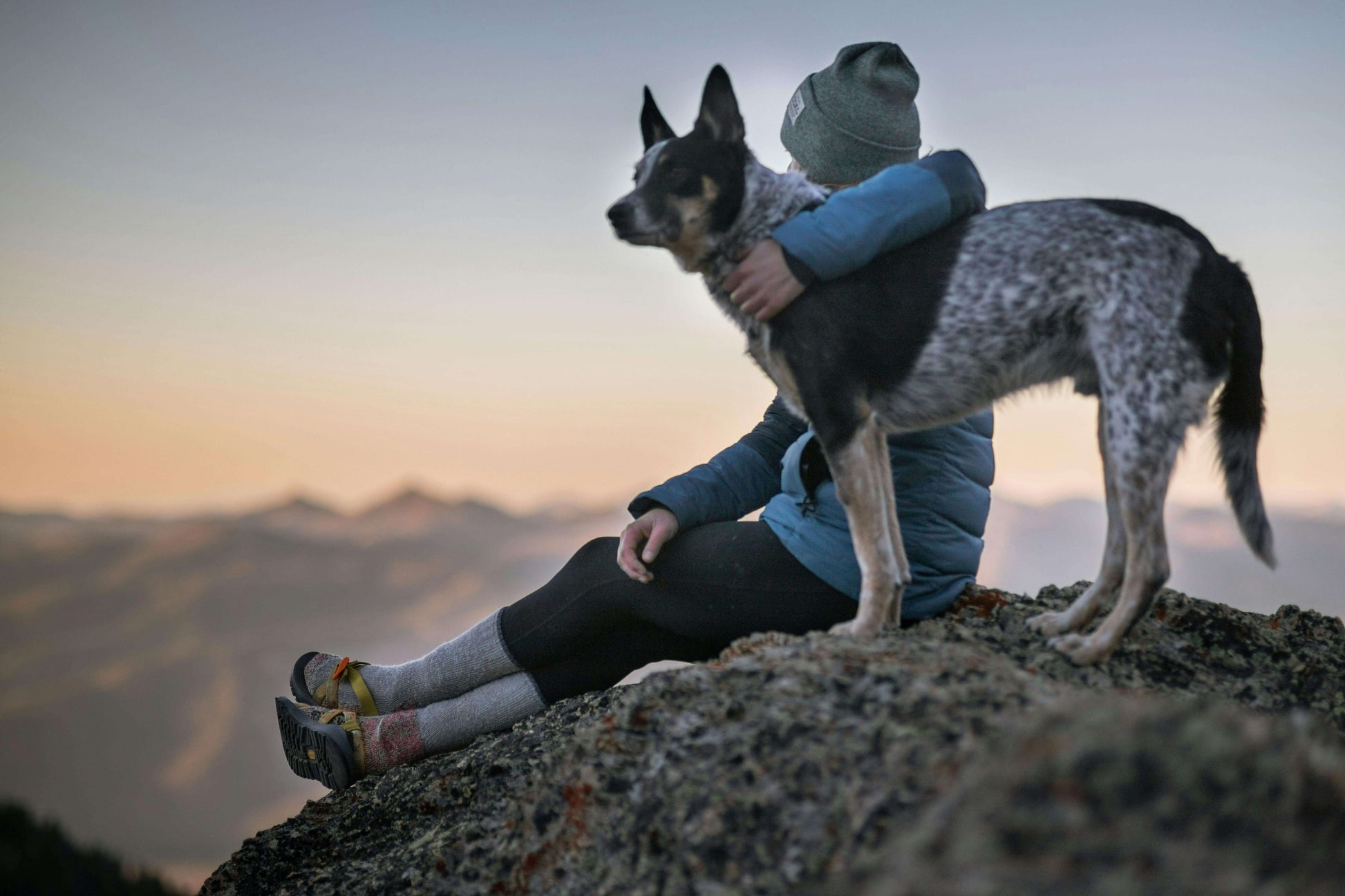 Woman celebrating a hike with her dog on a mountain summit.
