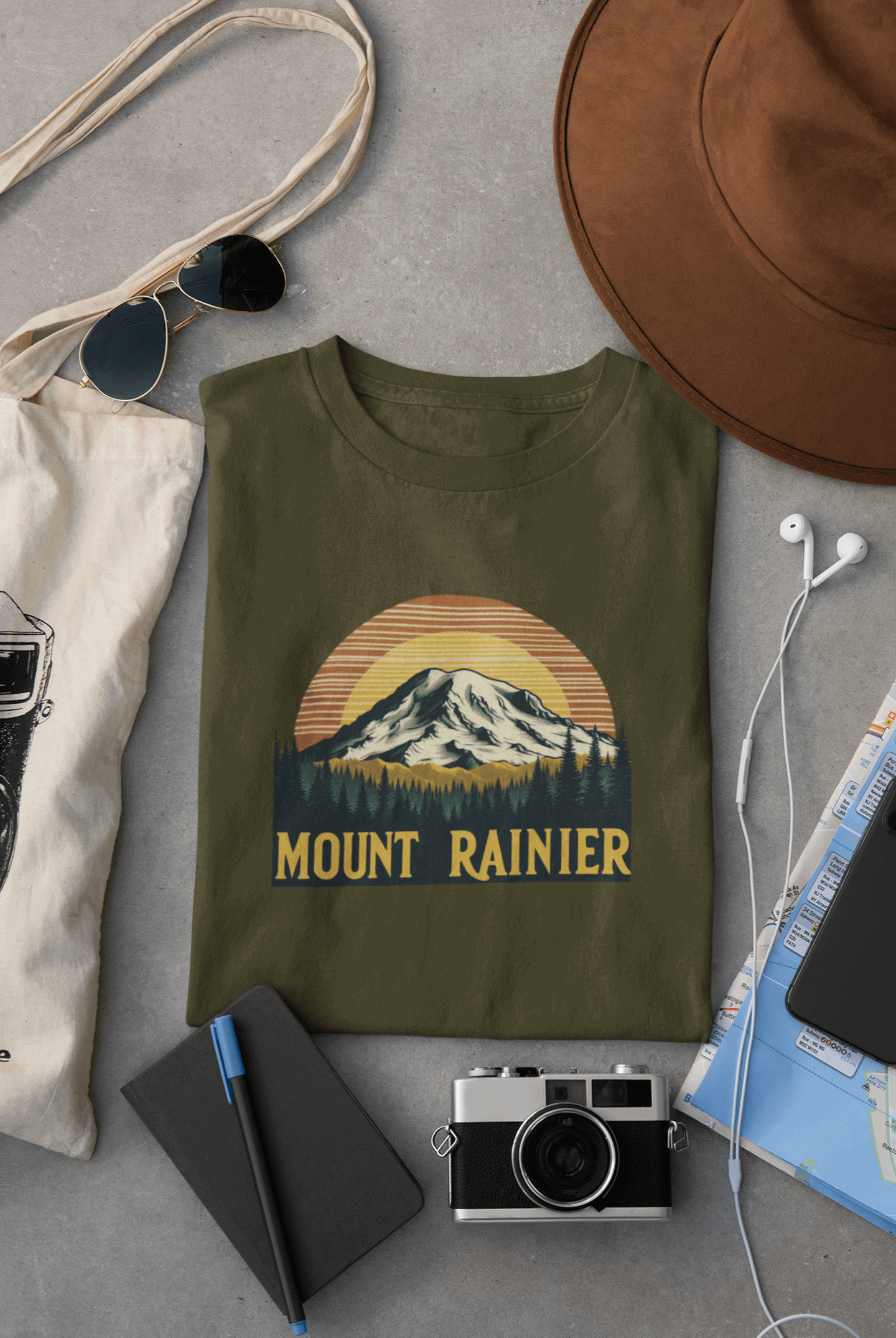 Wyld Peak Mount Rainier National Park organic cotton tee in military green laid flat on desk.