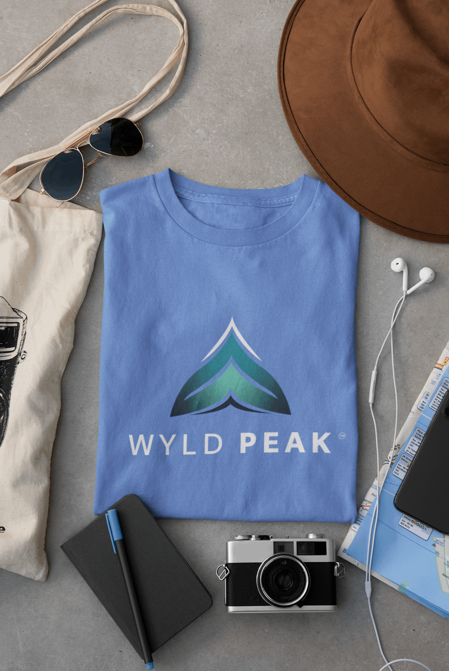 Blue Wyld Peak women’s branded tee laid flat on desk.