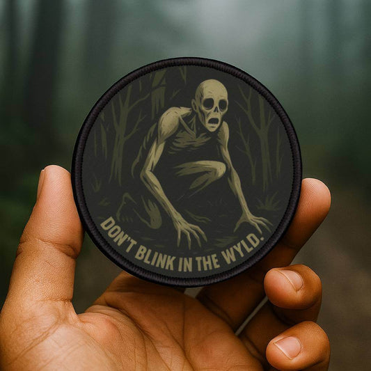 Wyld Peak Rake patch being held in a dark wooded forest scene
